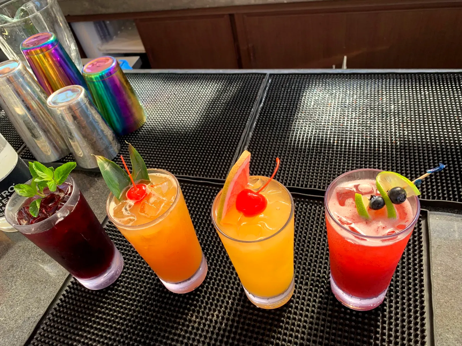 Cuatro cocteles de colores en la barra
